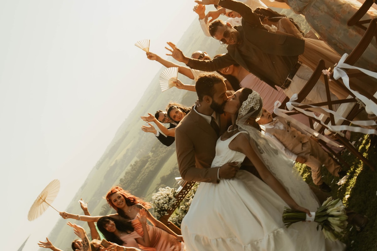 Wedding guests capturing the moment with their phones as the couple kisses