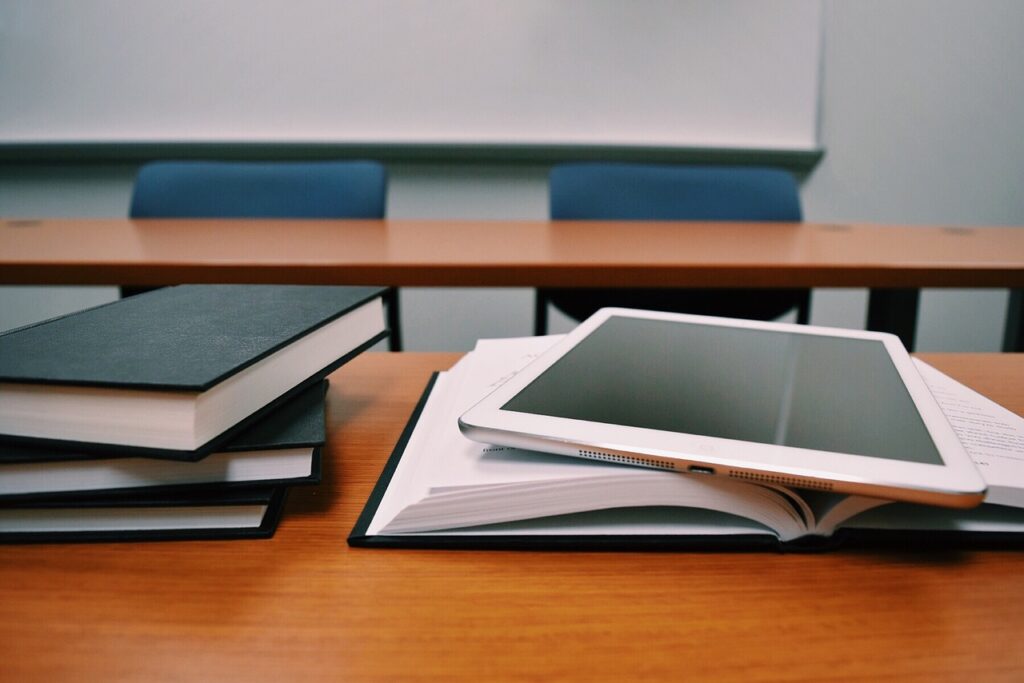 Photo of a tablet and some books on a school desk.